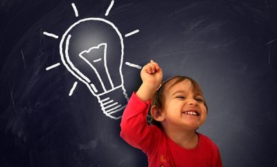 Little cute girl having a good idea on the blackboard - Learning and discovery concept with lightbulb